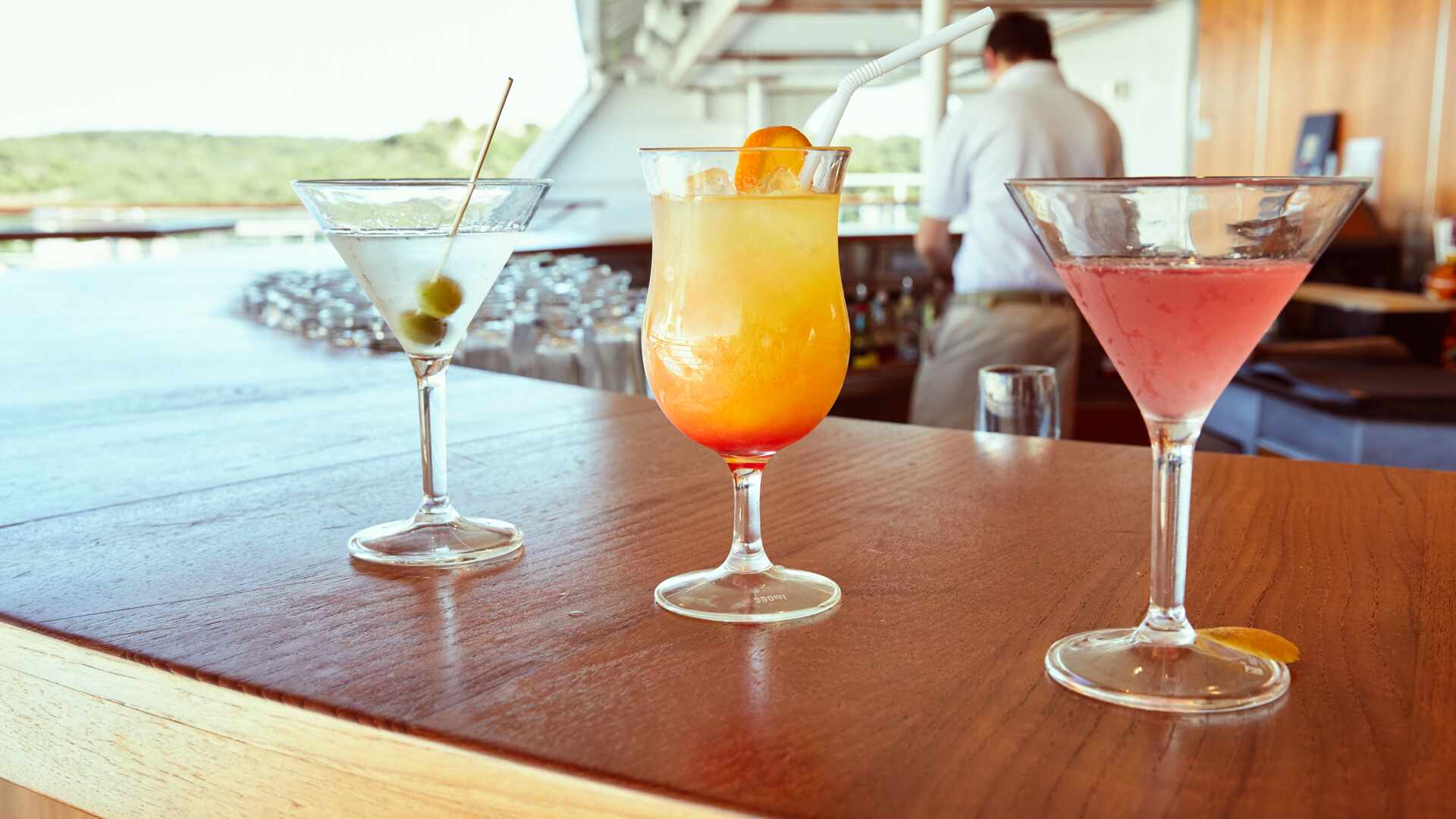 Close up of some cocktails at the bar with a bartender in the background